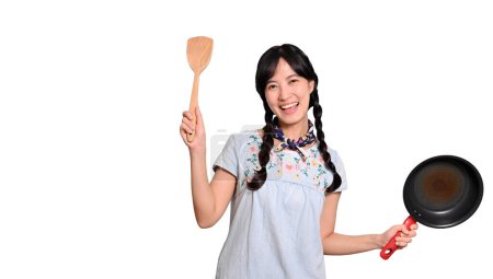 Photo for Portrait beautiful young asian woman wear denim dress with black pan and spatula on white isolated background - Royalty Free Image