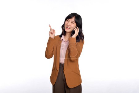 Photo for Young business asian woman listening to mobile phone and pointing finger to free copy space isolated on white background - Royalty Free Image
