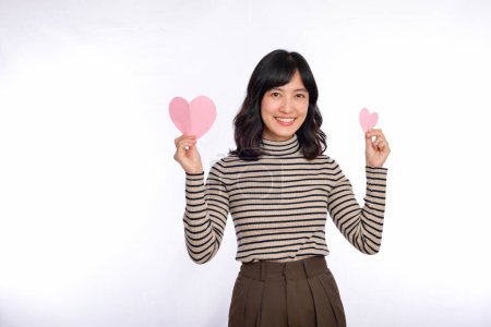 Photo for Beautiful young asian woman with paper heart. Beautiful young asian woman holding a paper heart while standing against white background - Royalty Free Image