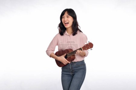 Photo for Happy young asian woman with casual clothing playing ukulele isolated on white background - Royalty Free Image