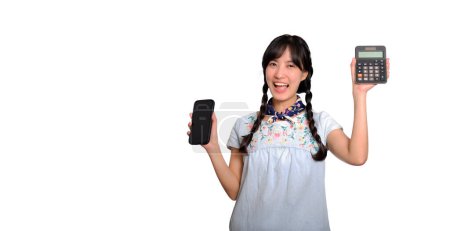 Téléchargez les photos : Portrait of beautiful happy young asian woman in denim dress holding calculator and smartphone on white background. business shopping online concept. - en image libre de droit