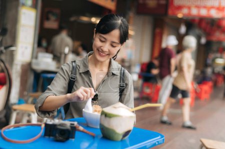 Téléchargez les photos : Happy young Asian woman backpack traveler enjoying street food at China town street food market in Bangkok, Thailand. - en image libre de droit