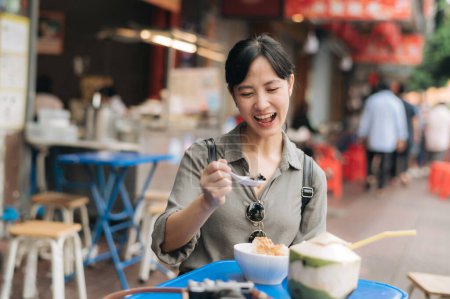 Foto de Feliz joven mujer asiática mochila viajero disfrutando de comida callejera en China ciudad mercado de alimentos en Bangkok, Tailandia. - Imagen libre de derechos