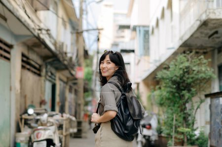 Téléchargez les photos : Jeune voyageuse asiatique sac à dos appréciant la rue lieu culturel local et sourire. Voyageur vérifiant les rues latérales. - en image libre de droit