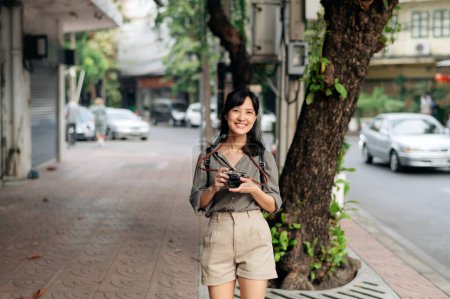 Téléchargez les photos : Young Asian woman backpack traveler using digital compact camera, enjoying street cultural local place and smile. - en image libre de droit