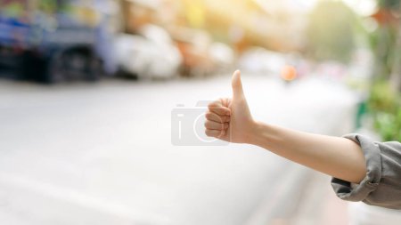 Foto de Sonriente joven mujer asiática viajero autoestop en un camino en la ciudad. - Imagen libre de derechos