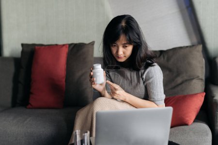 Téléchargez les photos : Malade asiatique femme avec médecine ayant vidéoconférence application médicale en télésanté sur ordinateur portable. - en image libre de droit