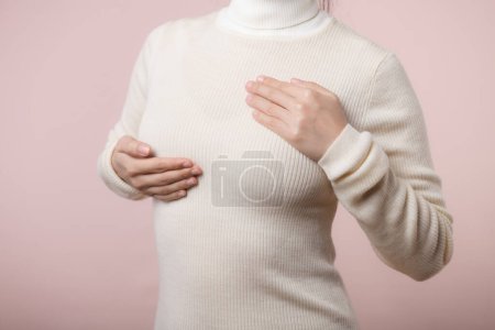 Photo for Woman hands checking lumps on her breast for signs of breast cancer on pink background. Healthcare concept. - Royalty Free Image