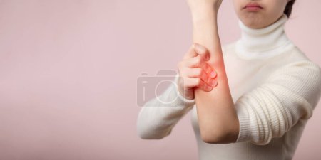 Téléchargez les photos : Asiatique jeune femme avec un pull en tissu blanc souffrant d'une blessure au bras. Les causes de blessures comprennent le syndrome du canal carpien, les fractures, l'arthrite ou le doigt déclencheur. Concept de soins de santé. - en image libre de droit