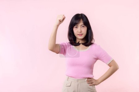 Foto de Retrato joven asiática mujer confiada y orgullosa mostrando fuerte fuerza muscular brazos flexionado posando, se siente acerca de su éxito logro. Empoderamiento de las mujeres, igualdad, fuerza saludable y concepto de valentía - Imagen libre de derechos