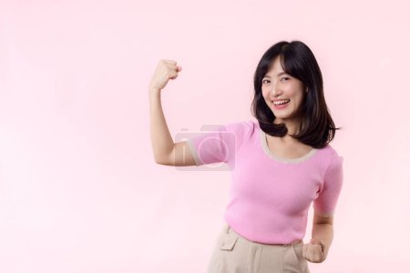 Foto de Retrato joven asiática mujer confiada y orgullosa mostrando fuerte fuerza muscular brazos flexionado posando, se siente acerca de su éxito logro. Empoderamiento de las mujeres, igualdad, fuerza saludable y concepto de valentía - Imagen libre de derechos