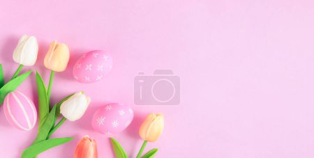 Photo for Happy Easter holiday greeting card concept. Colorful Easter Eggs and spring flowers on pastel pink background. Top view, flat lay, copy space. - Royalty Free Image
