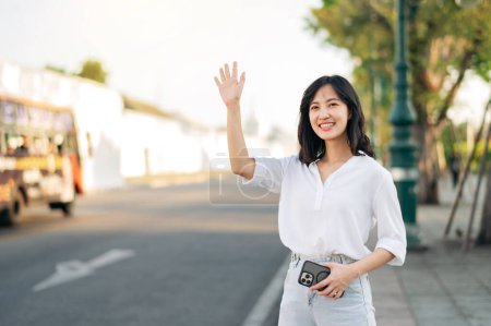 Téléchargez les photos : Portrait jeune belle asiatique femme agitant la main à ami par la rue dans un ensoleillé vacances. - en image libre de droit