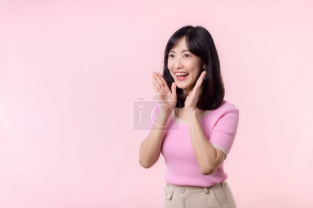 Téléchargez les photos : Portrait jeune belle asiatique femme expression yel hurler annoncer nouvelles de message de communication ou crier voix forte avec la main à côté de la bouche geste isolé sur fond rose pastel. - en image libre de droit
