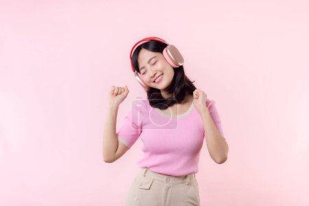 Photo for Smile pretty model person listen music song and enjoy dance with wireless headphone online audio radio sound. Positive exited fun joyful youth female woman sing on pink isolated background studio - Royalty Free Image