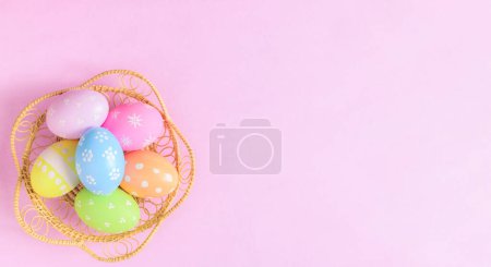 Foto de Feliz Pascua concepto tarjeta de felicitación vacaciones. Huevos de Pascua coloridos y flores de primavera sobre fondo rosa pastel. Vista superior, plano, espacio para copiar. - Imagen libre de derechos