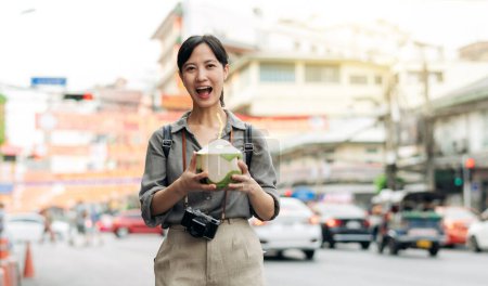 Photo for Happy young Asian woman backpack traveler drinking a coconut juice at China town street food market in Bangkok, Thailand. - Royalty Free Image