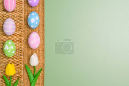 Téléchargez les photos : Bonne fête de Pâques concept de carte de voeux. Oeufs de Pâques colorés et fleurs de printemps sur fond vert pastel. Vue du dessus, plan, espace de copie. - en image libre de droit