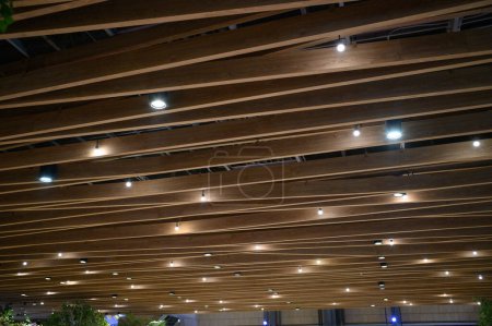Photo for Light ceiling with wood interior design. Wooden ceiling decor lamp in room, home indoor. Modern style material with plank, timber architecture in brown colour with electricity bulb meeting hall. - Royalty Free Image