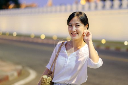 Téléchargez les photos : Portrait jeune belle femme asiatique souriant tout en voyageant au palais doré au crépuscule point de vue, Bangkok. - en image libre de droit
