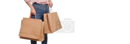 Téléchargez les photos : Gros plan de la main de la femme avec des vêtements décontractés tenant sac de papier shopping isolé sur fond blanc. Concept d'emballage écologique. - en image libre de droit