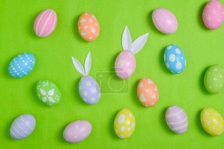 Photo for Happy Easter holiday greeting card concept. Colorful Easter Eggs and spring flowers on pastel green background. Top view, flat lay, copy space. - Royalty Free Image