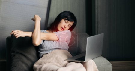 Photo for Asian woman has shoulder pain while working on laptop at home. People with body-muscles problem. - Royalty Free Image