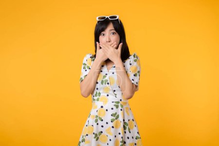 Photo for Portrait young asian woman hushing with hand sign shares secret makes taboo gesture wears casual springtime dress isolated on yellow background. Shh be quiet concept - Royalty Free Image