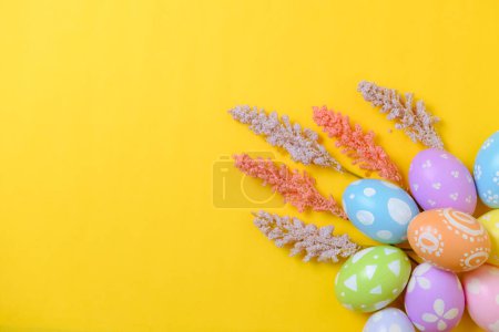 Foto de Feliz Pascua concepto tarjeta de felicitación vacaciones. Huevos de Pascua coloridos y flores de primavera sobre fondo amarillo. Vista superior, plano, espacio para copiar. - Imagen libre de derechos
