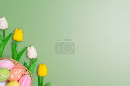 Téléchargez les photos : Bonne fête de Pâques concept de carte de voeux. Oeufs de Pâques colorés et fleurs de printemps sur fond vert pastel. Vue du dessus, plan, espace de copie. - en image libre de droit