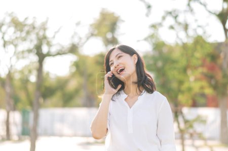 Téléchargez les photos : Portrait belle jeune femme asiatique avec téléphone portable intelligent autour de la vue extérieure de la nature dans la journée ensoleillée d'été - en image libre de droit