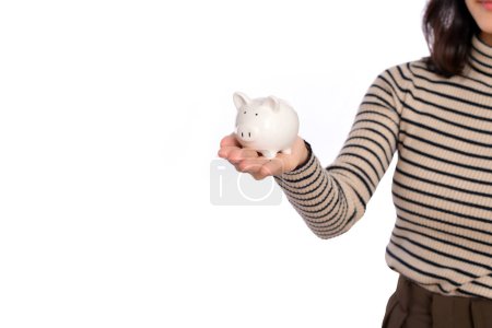 Téléchargez les photos : Portrait de jeune femme asiatique tenant tirelire blanche isolée sur fond blanc, concept d'épargne financière et bancaire - en image libre de droit