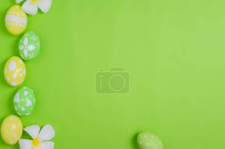 Photo for Happy Easter holiday greeting card concept. Colorful Easter Eggs and spring flowers on pastel green background. Top view, flat lay, copy space. - Royalty Free Image