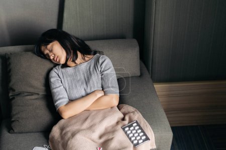 Téléchargez les photos : Femme asiatique avec froid et grippe dormir sur canapé-lit. - en image libre de droit