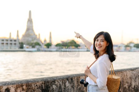 Foto de Retrato hermosa mujer asiática sonriendo mientras viaja en Wat Arun sunset punto de vista, Bangkok, Tailandia. - Imagen libre de derechos
