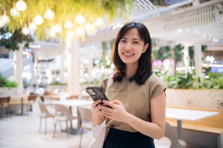Photo for Portrait beautiful young asian woman with smart mobile phone in cafeteria at a shopping mall. - Royalty Free Image