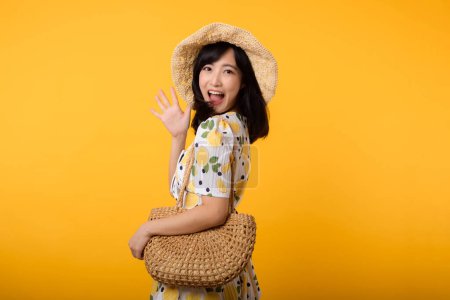 Photo for Portrait attractive happy young asian woman with trendy springtime dress, hat, sunglasses fashion and woven bag isolated on yellow background. Summertime sale shopping concept. - Royalty Free Image