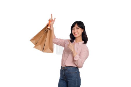Photo for Young happy asian woman with casual shirt and denim jeans holding shopping paper bag isolated on white background. - Royalty Free Image