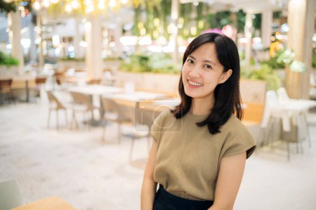 Foto de Smiling beautiful asian woman standing in cafeteria at shopping mall. - Imagen libre de derechos