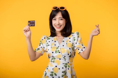 Photo for Portrait asian young woman happy smiling in springtime dress showing plastic credit card isolated on yellow background. Pay, money and purchase shopping payment concept. - Royalty Free Image