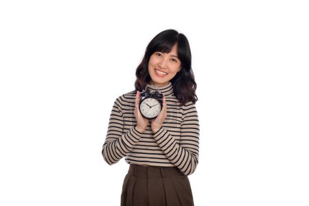 Foto de Mujer asiática feliz con ropa casual sosteniendo reloj despertador sobre fondo blanco. - Imagen libre de derechos