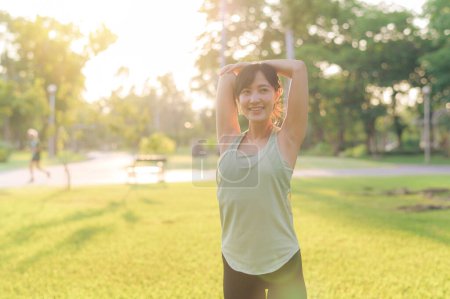 Photo for Female jogger. Fit Asian young woman with green sportswear stretching muscle in park before running and enjoying a healthy outdoor. Fitness runner girl in public park. Wellness being concept - Royalty Free Image