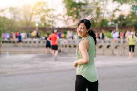 Foto de Una corredora. Ajuste Mujer joven asiática con ropa deportiva verde aeróbic ejercicio de baile en el parque y disfrutar de un sano al aire libre. Chica corredor de fitness en el parque público. Bienestar siendo concepto - Imagen libre de derechos