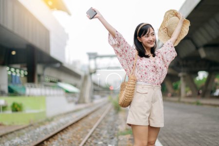 Foto de Asiático joven viajero con tejer cesta feliz sonriendo mirando a una cámara junto tren ferrocarril. Viaje viaje estilo de vida, viajero mundial o concepto de turismo de verano de Asia. - Imagen libre de derechos