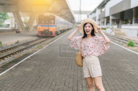 Photo for Asian young woman traveler with weaving basket happy smiling and looking to a camera beside train coming background. Journey trip lifestyle, world travel explorer or Asia summer tourism concept. - Royalty Free Image