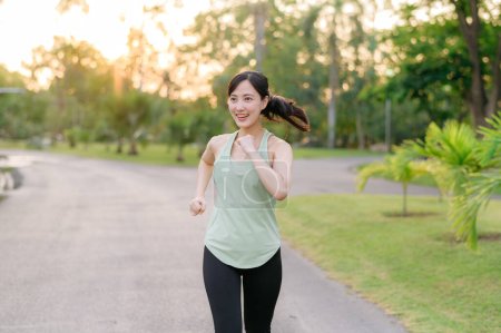 Photo for Fit young Asian woman jogging in park smiling happy running and enjoying a healthy outdoor lifestyle. Female jogger. Fitness runner girl in public park. healthy lifestyle and wellness being concept - Royalty Free Image