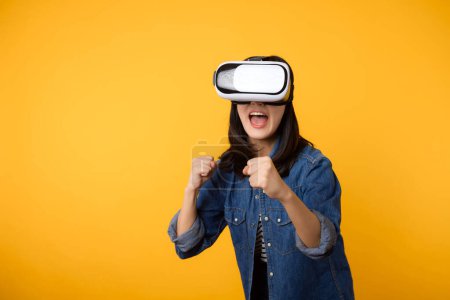 Téléchargez les photos : Asiatique jeune femme obtenir expérimenté portant réalité virtuelle jeu de casque divertissement isolé sur fond jaune. Gagnant du concept de cyberfutur jeu vidéo. - en image libre de droit