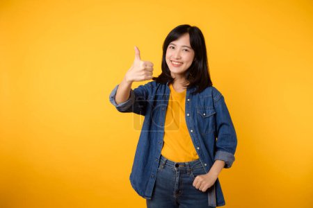 Photo for Portrait happy young asian woman cheerful smile showing thumb up, trust, recommend gesture isolated on yellow studio background. Pretty attractive female with like hand sign. lifestyle girl woman - Royalty Free Image