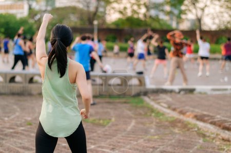 Téléchargez les photos : Joggeuse. Adaptez-vous à une jeune femme asiatique avec des vêtements de sport verts exercice de danse aérobie dans le parc et profiter d'un plein air sain. Fitness fille coureuse dans le parc public. Concept de bien-être - en image libre de droit