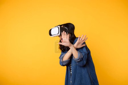 Téléchargez les photos : Asiatique jeune femme obtenir expérimenté portant réalité virtuelle jeu de casque divertissement isolé sur fond jaune. Gagnant du concept de cyberfutur jeu vidéo. - en image libre de droit